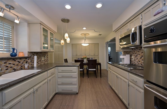 kitchen featuring appliances with stainless steel finishes, decorative light fixtures, backsplash, and sink