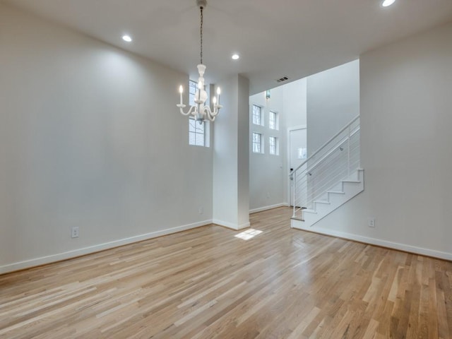 unfurnished room featuring a notable chandelier and light hardwood / wood-style flooring