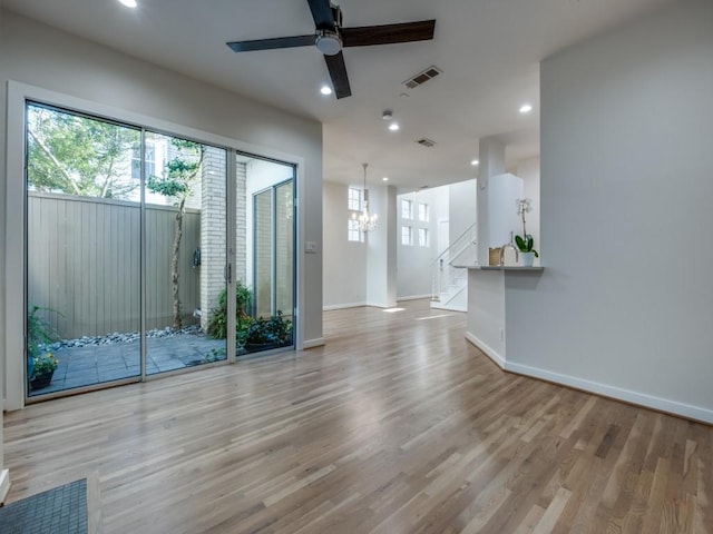 spare room featuring light wood-type flooring and ceiling fan with notable chandelier