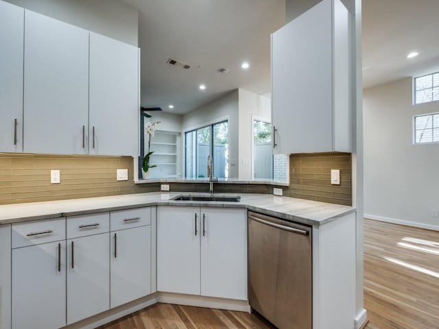 kitchen with white cabinets, kitchen peninsula, dishwasher, and sink