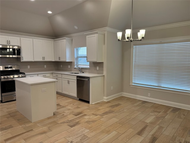 kitchen featuring vaulted ceiling, white cabinetry, sink, a center island, and stainless steel appliances