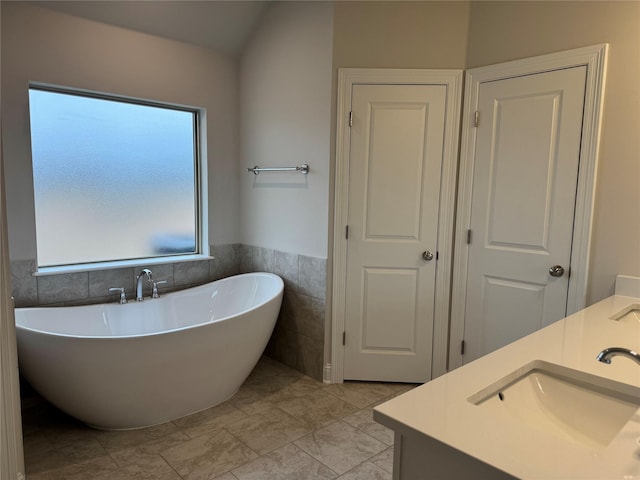 bathroom with a bath, vanity, tile patterned flooring, and tile walls