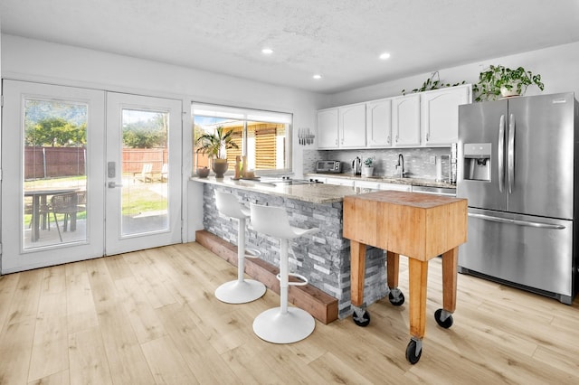 kitchen with stainless steel appliances, white cabinetry, a textured ceiling, decorative backsplash, and plenty of natural light