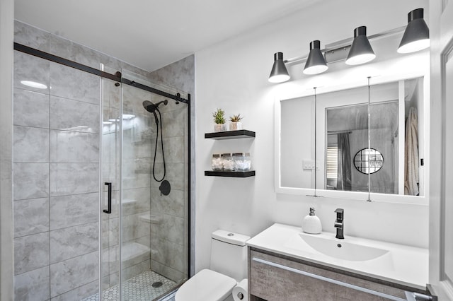 bathroom with toilet, vanity, and a shower with shower door