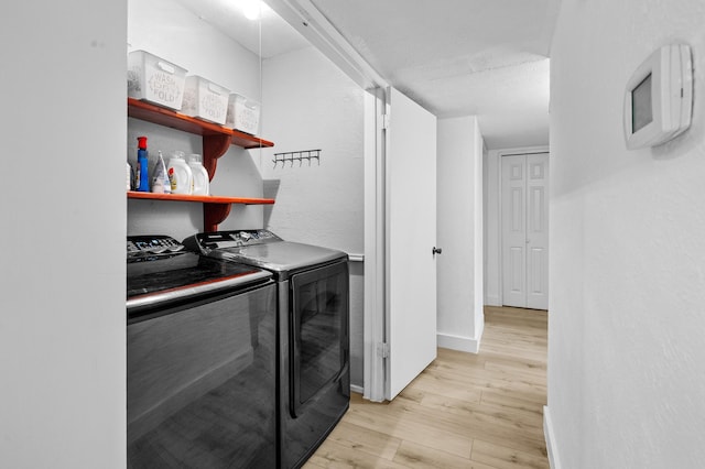 clothes washing area with washer and clothes dryer and light wood-type flooring