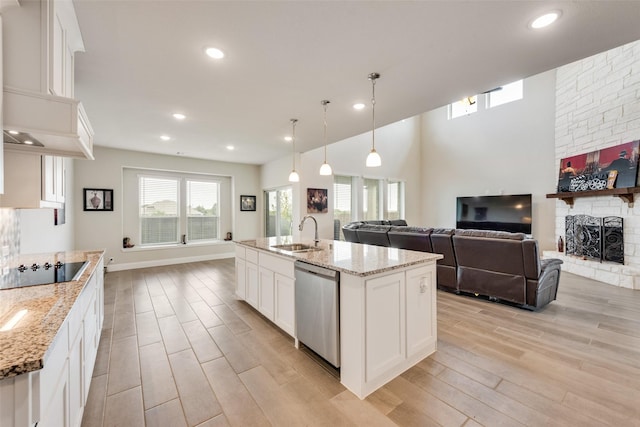 kitchen featuring stainless steel dishwasher, a center island with sink, and white cabinetry