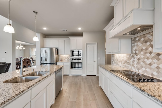 kitchen with sink, white cabinetry, custom range hood, pendant lighting, and appliances with stainless steel finishes