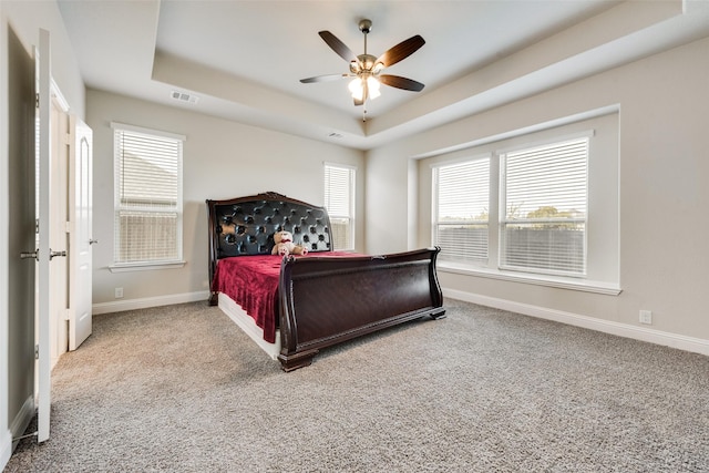 bedroom with carpet floors, ceiling fan, and a tray ceiling