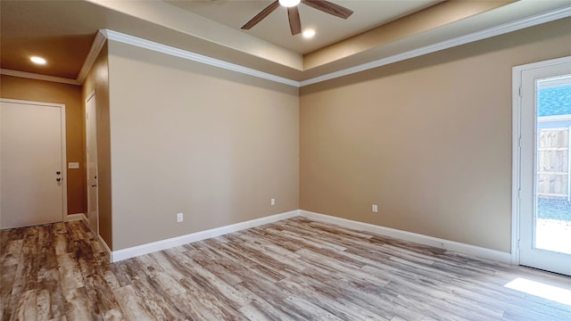 spare room featuring crown molding, ceiling fan, a tray ceiling, and light wood-type flooring