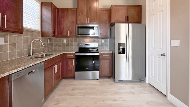 kitchen featuring sink, tasteful backsplash, light wood-type flooring, stainless steel appliances, and light stone countertops