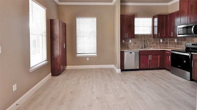 kitchen with tasteful backsplash, sink, stainless steel appliances, crown molding, and light hardwood / wood-style flooring