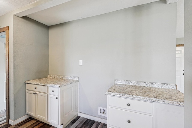 kitchen with white cabinets, dark wood-type flooring, and light stone countertops