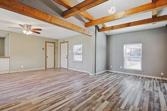 unfurnished room with light wood-type flooring, beam ceiling, ceiling fan, and plenty of natural light