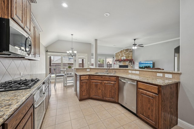 kitchen with stainless steel appliances, light stone countertops, sink, lofted ceiling, and ceiling fan with notable chandelier