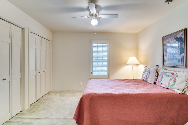 carpeted bedroom with ceiling fan and multiple closets