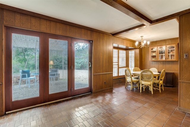 dining area featuring beamed ceiling, an inviting chandelier, and wood walls