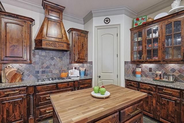 kitchen featuring stainless steel gas stovetop, wood counters, decorative backsplash, and dark brown cabinets