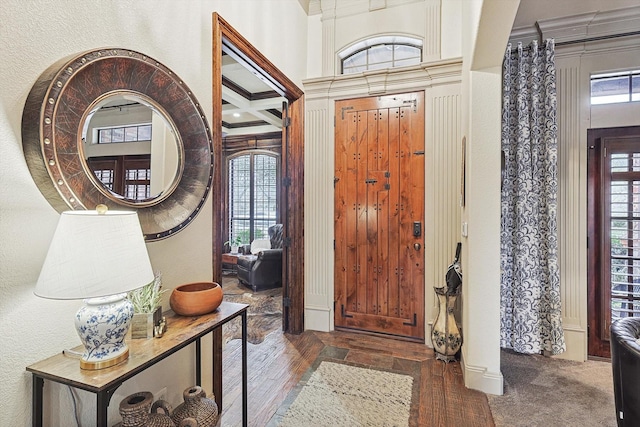 carpeted foyer entrance featuring crown molding and plenty of natural light