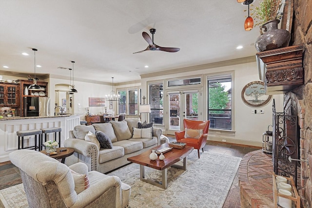 living room featuring crown molding, ceiling fan with notable chandelier, and sink