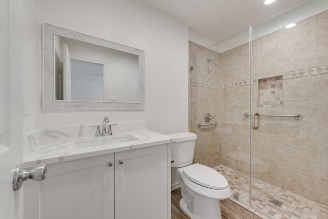 bathroom with wood-type flooring, walk in shower, vanity, and toilet