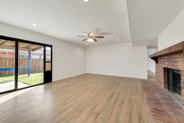 unfurnished living room with a fireplace, light wood-type flooring, and ceiling fan