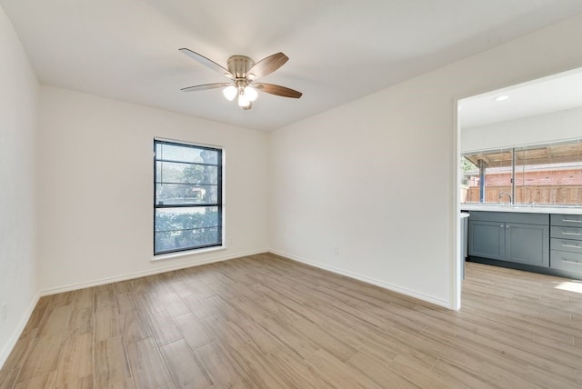 empty room featuring sink, light wood-type flooring, and ceiling fan