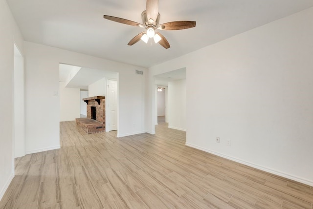 unfurnished living room featuring a fireplace, ceiling fan, and light hardwood / wood-style floors