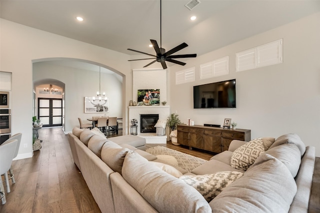 living room with a large fireplace, dark hardwood / wood-style floors, and ceiling fan with notable chandelier