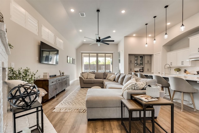 living room featuring ceiling fan, light wood-type flooring, and a high ceiling