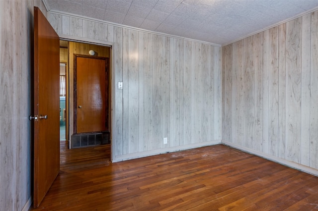 empty room with dark wood-type flooring and wooden walls