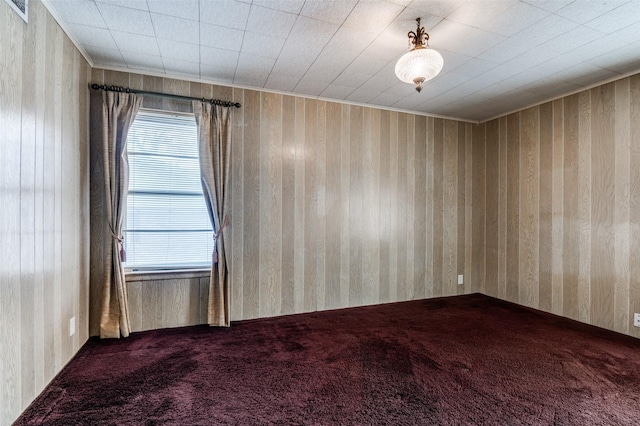 unfurnished room with carpet flooring, wood walls, and a wealth of natural light