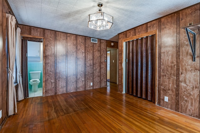 foyer with hardwood / wood-style floors, wooden walls, and a chandelier