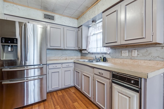 kitchen with tile counters, gray cabinetry, stainless steel fridge with ice dispenser, dark hardwood / wood-style flooring, and sink