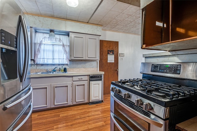 kitchen with stainless steel appliances, sink, light wood-type flooring, and gray cabinetry