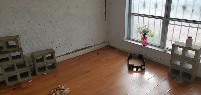 empty room featuring brick wall and hardwood / wood-style flooring