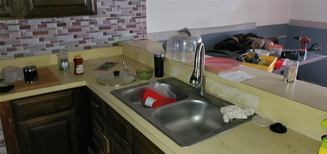 kitchen featuring sink, backsplash, and dark brown cabinetry