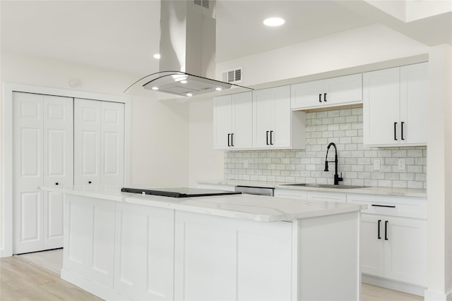 kitchen with sink, decorative backsplash, white cabinets, and island range hood