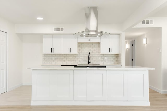 kitchen featuring white cabinets, backsplash, and island range hood