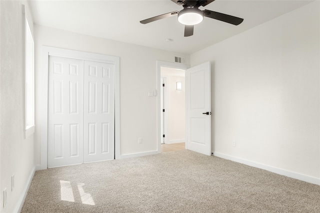 unfurnished bedroom featuring ceiling fan, a closet, and light carpet