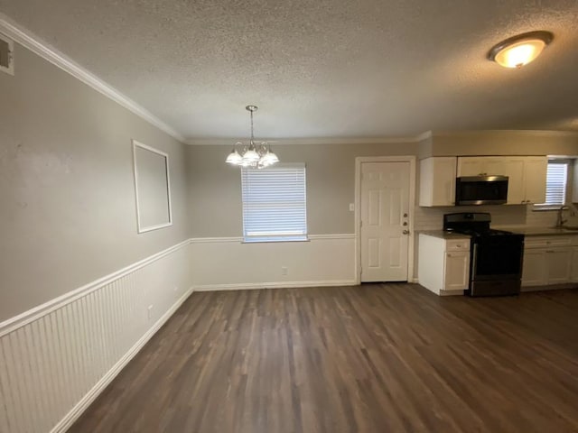 kitchen with white cabinets, ornamental molding, black gas stove, and hanging light fixtures