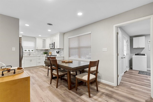 dining room featuring sink, light wood-type flooring, and washer / clothes dryer