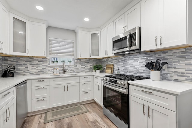 kitchen with stainless steel appliances, decorative backsplash, white cabinets, and sink