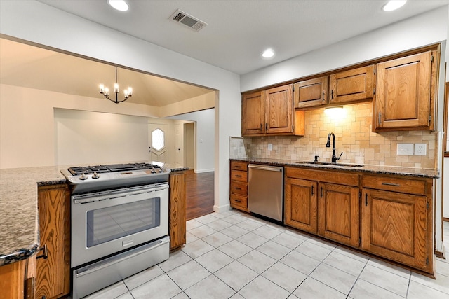 kitchen featuring appliances with stainless steel finishes, light tile patterned floors, a notable chandelier, sink, and decorative light fixtures