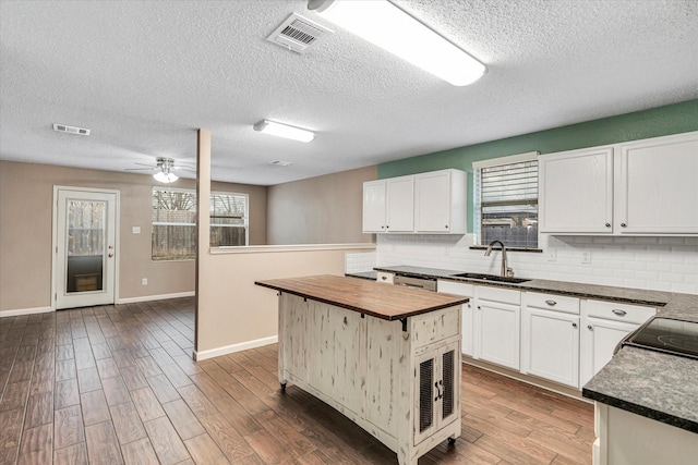 kitchen with white cabinetry, sink, a kitchen island, and backsplash