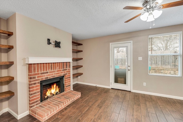 unfurnished living room with dark hardwood / wood-style flooring, ceiling fan, a fireplace, and a textured ceiling