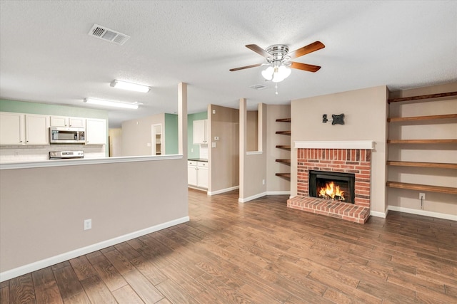 unfurnished living room with ceiling fan, hardwood / wood-style flooring, a fireplace, and a textured ceiling