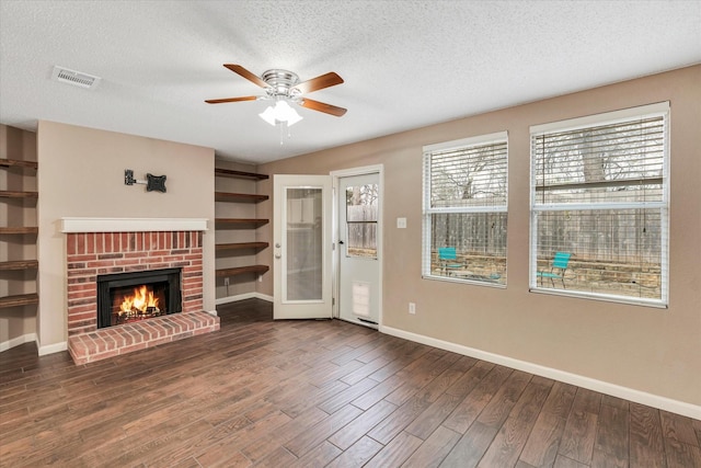 unfurnished living room featuring ceiling fan, dark wood-type flooring, a fireplace, and a textured ceiling