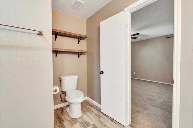 bathroom featuring ceiling fan, toilet, and a textured ceiling