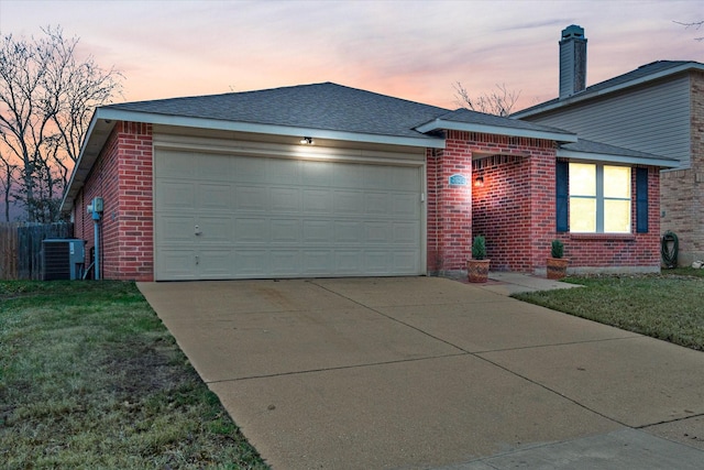 ranch-style home featuring cooling unit, a yard, and a garage