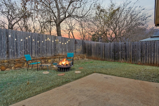 yard at dusk featuring a patio and an outdoor fire pit